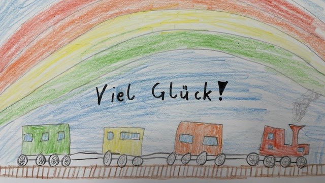 Kinderzeichnung mit einem weihnachtlichen Zug für Krebspatienten unter einem Regenbogen und dem Wunsch "Viel Glück!"