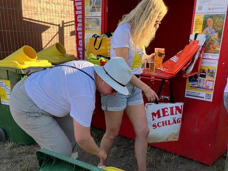 ehrenamtliche Mitarbeiterinnen mit Spendentonne vor der Spendenh&uuml;tte