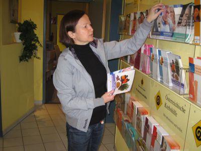 Frau nimmt sich Broschüren von einer Broschürenwand