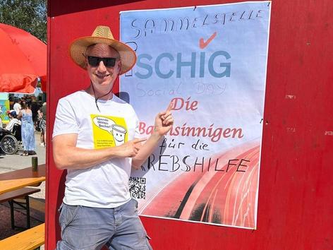 ehrenamtlicher Mitarbeiter der Firma SCHIG mbH mit eigens gestaltetem Plakat über den Social Day für die Krebshilfe Wien