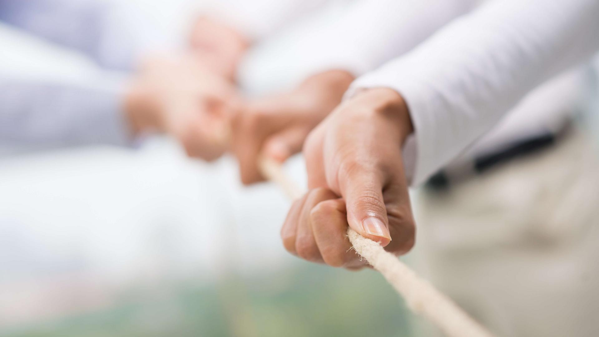 Hände halten gemeinsam ein Seil