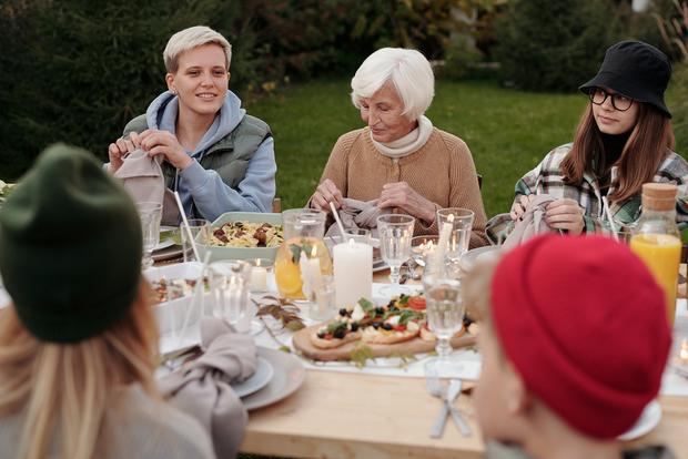 eine ältere Dame sitzt mit jungen Frauen und Kindern an einem gedeckten Tisch