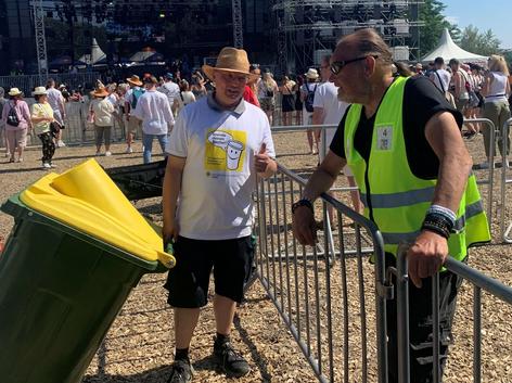 Erhenamtlicher unterwegs mit Spendentonne, im Hintergrund eine Bühne