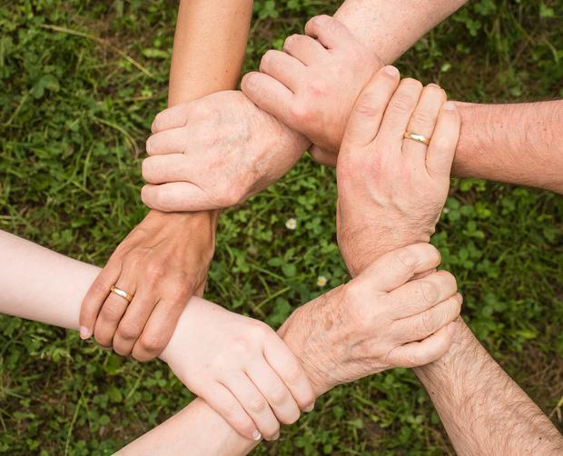 ein Kreis gebildet aus sechs H&auml;nden, die das Handgelenk eines anderen umfassen